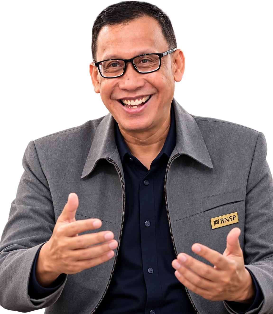 Joko Wahyono tersenyum sambil menjelaskan, mengenakan jaket abu-abu dan kemeja gelap